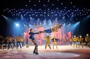 Eisläufer, die Kunststücke machen, blauer Hintergrund mit Spots auf die in mit viel Gold und blau gekleideten Eisläufer